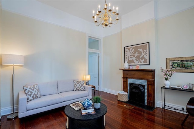 living room featuring a brick fireplace, dark wood-type flooring, and a chandelier