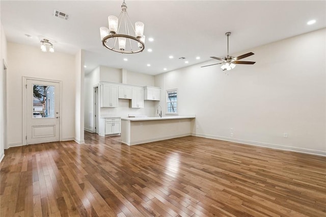 unfurnished living room with dark hardwood / wood-style flooring, sink, and ceiling fan with notable chandelier