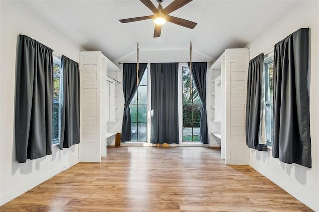 spare room featuring vaulted ceiling, a healthy amount of sunlight, and light wood-type flooring