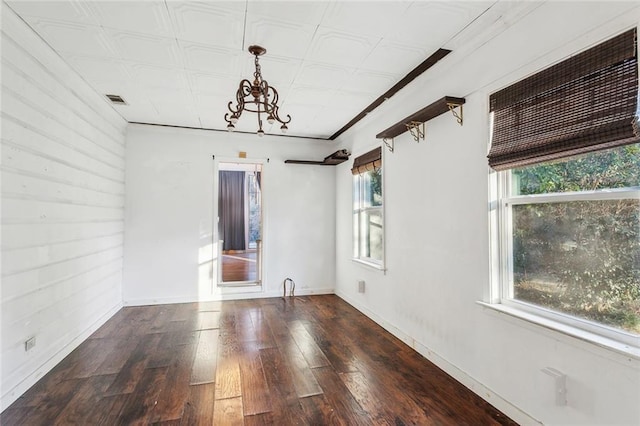 unfurnished room featuring dark hardwood / wood-style flooring and an inviting chandelier