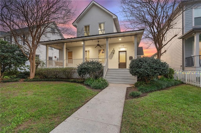 view of front of house featuring ceiling fan, a yard, and covered porch