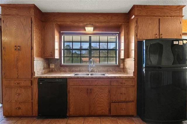 kitchen with sink, light tile patterned floors, black appliances, and a textured ceiling