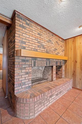 room details featuring a brick fireplace, a textured ceiling, and wood walls