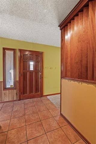 tiled entrance foyer featuring a textured ceiling and wood walls