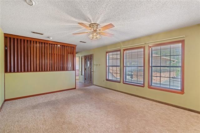 empty room with a textured ceiling, light colored carpet, and ceiling fan