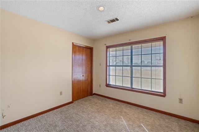 carpeted spare room featuring a textured ceiling