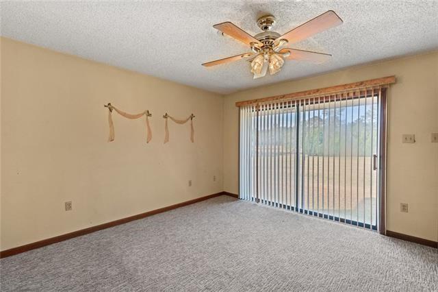 carpeted spare room featuring ceiling fan and a textured ceiling