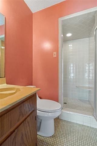 bathroom featuring tile patterned flooring, vanity, a shower with door, and toilet