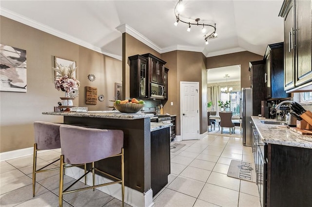 kitchen with light tile patterned floors, a breakfast bar area, appliances with stainless steel finishes, light stone counters, and ornamental molding