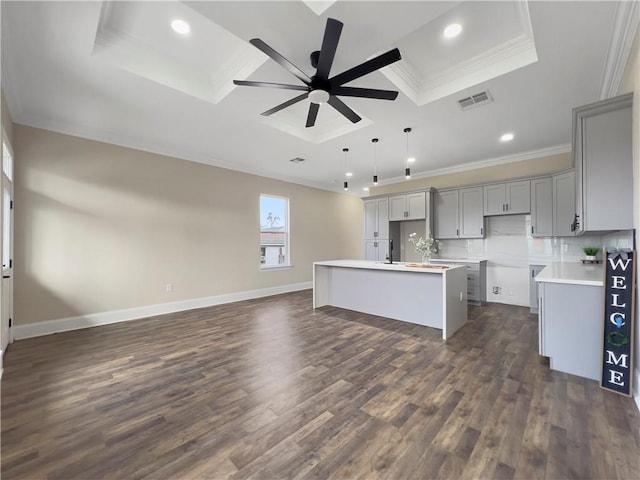 kitchen with pendant lighting, crown molding, gray cabinets, a center island with sink, and dark hardwood / wood-style flooring