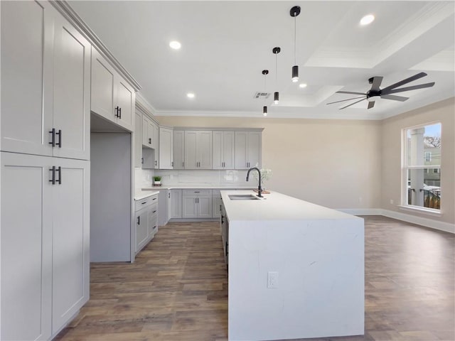 kitchen featuring hardwood / wood-style floors, sink, hanging light fixtures, a kitchen island with sink, and crown molding