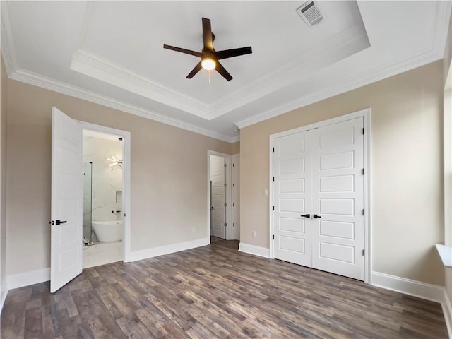 unfurnished bedroom with dark hardwood / wood-style floors, a raised ceiling, and a closet