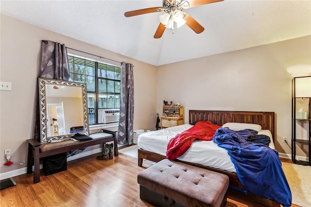 bedroom with lofted ceiling, cooling unit, wood-type flooring, and ceiling fan