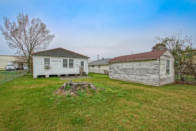 back of house with cooling unit, a storage shed, and a yard