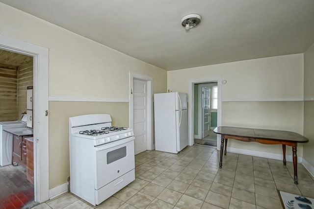 kitchen featuring light tile patterned flooring, washer / dryer, and white appliances