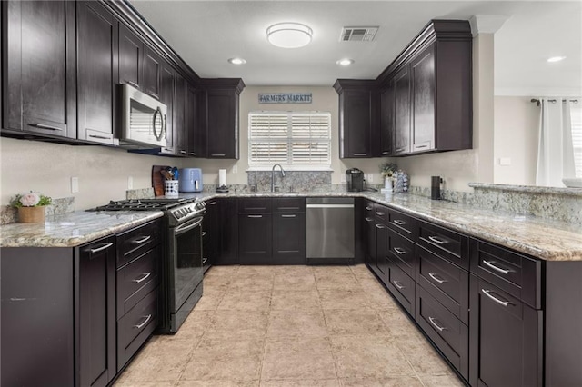 kitchen with sink, stainless steel appliances, a healthy amount of sunlight, and light stone countertops