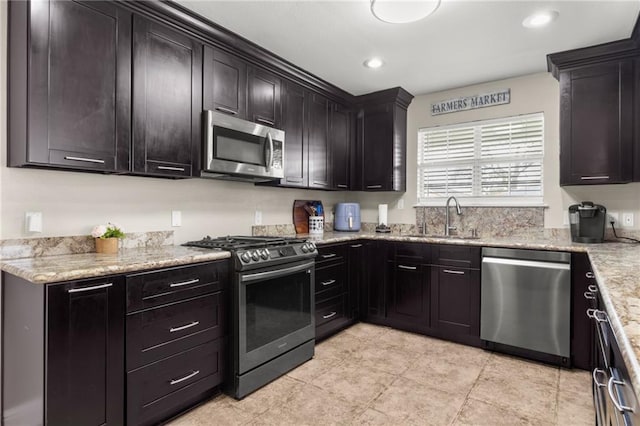 kitchen with stainless steel appliances, light stone countertops, sink, and dark brown cabinetry