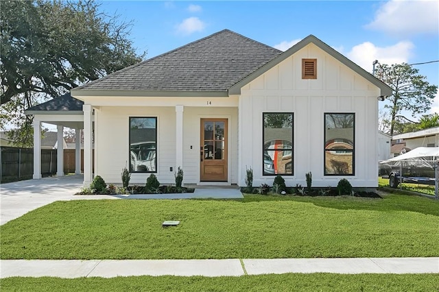 modern inspired farmhouse with a front yard, a carport, and a porch