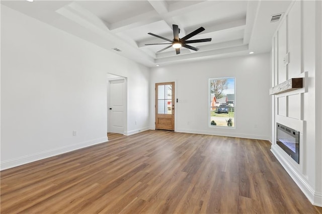 unfurnished living room featuring coffered ceiling, wood-type flooring, beamed ceiling, ceiling fan, and a fireplace