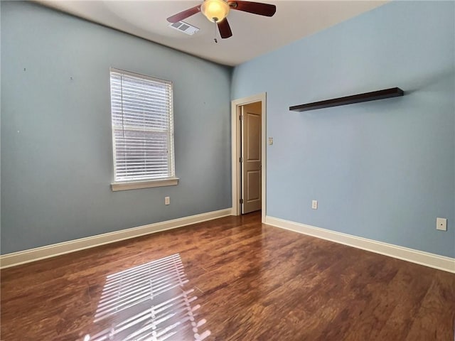 spare room featuring ceiling fan, dark wood-style flooring, visible vents, and baseboards