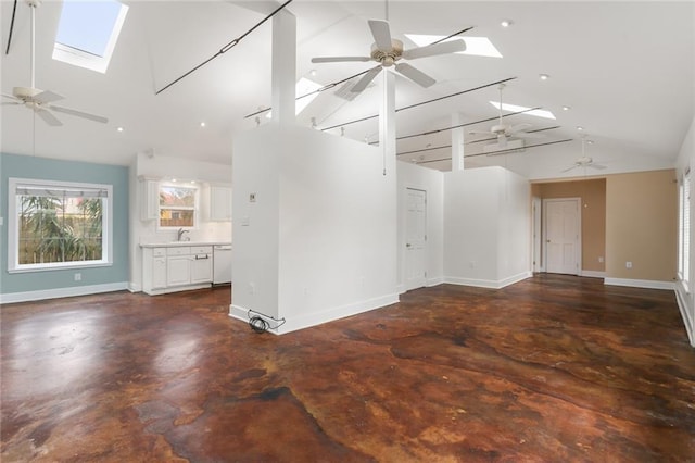 unfurnished living room with ceiling fan, sink, a skylight, and high vaulted ceiling