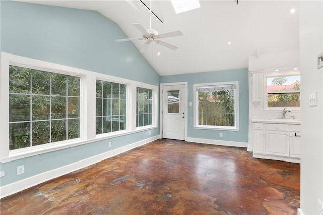 unfurnished sunroom featuring ceiling fan, vaulted ceiling with skylight, and sink