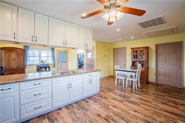 kitchen with white cabinetry, sink, hardwood / wood-style flooring, and light stone counters