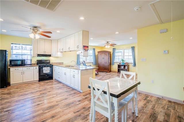 kitchen with sink, white cabinets, light stone counters, and black appliances