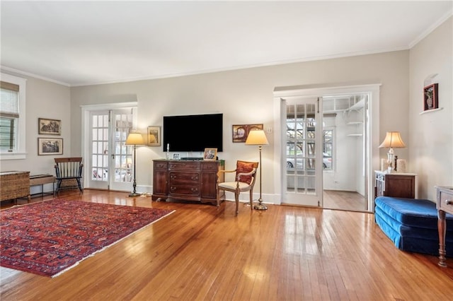 living room with light hardwood / wood-style flooring, ornamental molding, and french doors