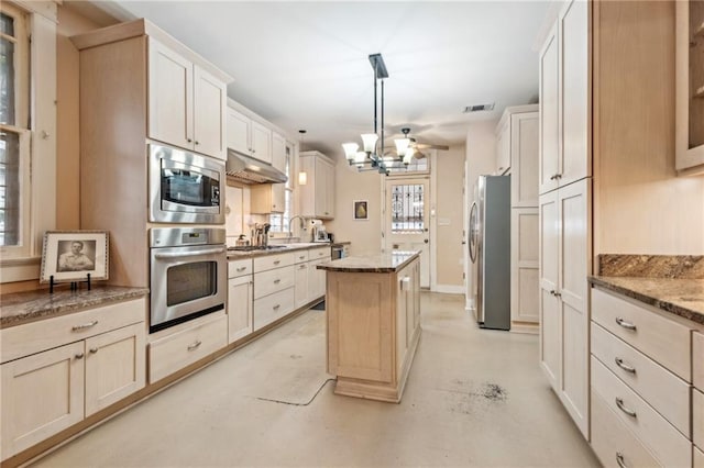 kitchen with light stone counters, a center island, a notable chandelier, pendant lighting, and stainless steel appliances