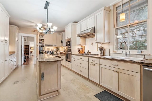 kitchen with stainless steel appliances, sink, dark stone countertops, and decorative light fixtures