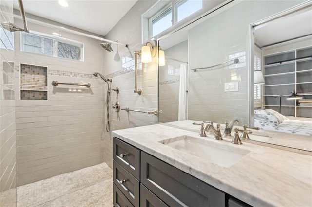 bathroom with a healthy amount of sunlight, vanity, and a tile shower