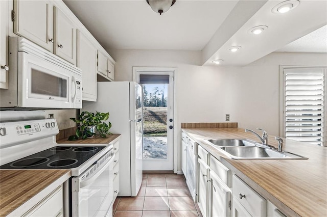 kitchen with butcher block countertops, sink, white appliances, light tile patterned floors, and white cabinets