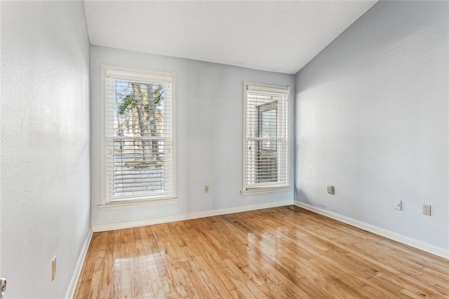 spare room with vaulted ceiling and light hardwood / wood-style floors