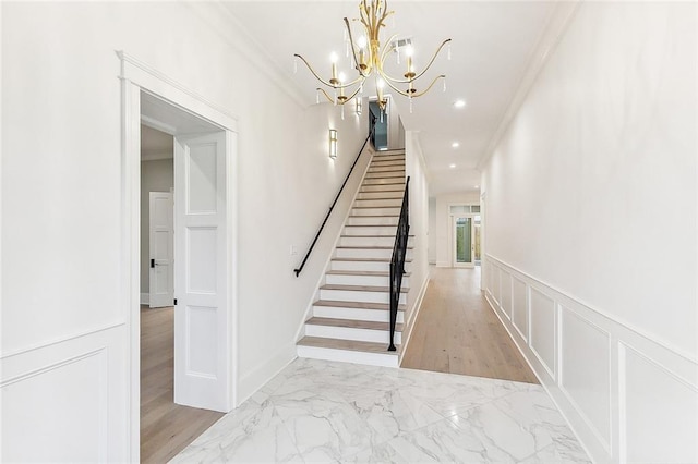 3705 Rue Emilion Dr, Metairie, LA 70002 - stairway with ornamental molding, a decorative wall, a wainscoted wall, a chandelier, and marble finish flooring