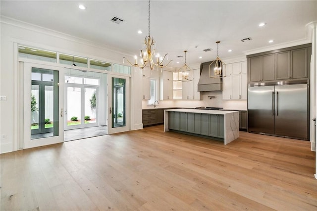 3705 Rue Emilion Dr, Metairie, LA 70002 - kitchen featuring stainless steel built in fridge, custom range hood, a chandelier, crown molding, and light countertops