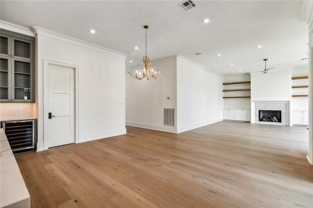 3705 Rue Emilion Dr, Metairie, LA 70002 - unfurnished living room featuring wine cooler, crown molding, ceiling fan, light wood-style floors, and a chandelier
