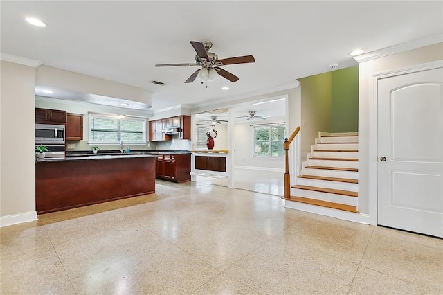 kitchen featuring dark countertops, stainless steel microwave, visible vents, baseboards, and light speckled floor