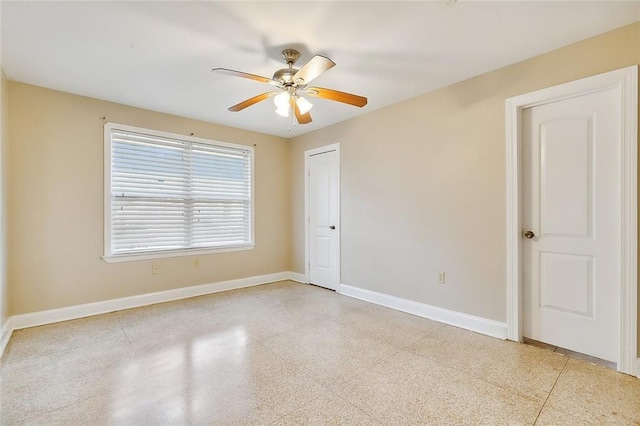 unfurnished room featuring baseboards, light speckled floor, and a ceiling fan