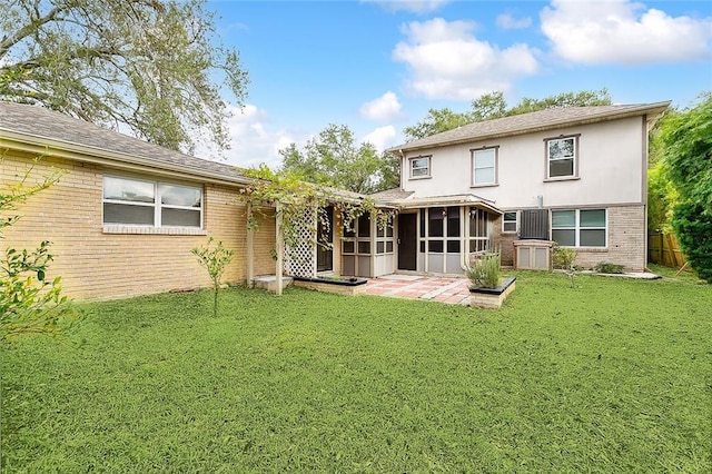 rear view of house with brick siding, fence, a yard, a sunroom, and a patio area