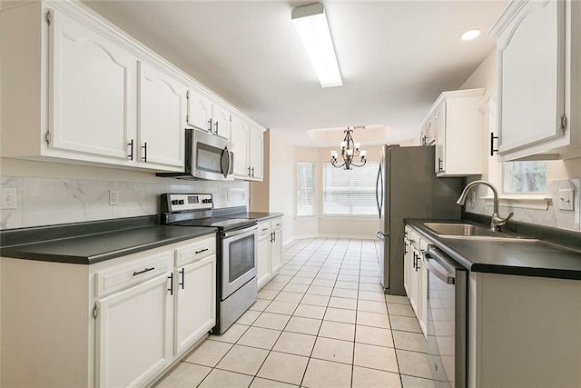 kitchen featuring stainless steel appliances, backsplash, light tile patterned floors, sink, and white cabinetry