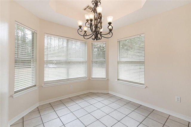 unfurnished dining area featuring a raised ceiling, a notable chandelier, and light tile patterned floors