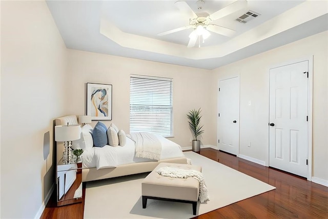 bedroom featuring a tray ceiling, ceiling fan, and dark wood-type flooring