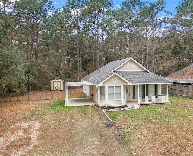 view of front of house with a porch, a storage unit, a carport, and a front yard