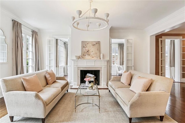 living room with hardwood / wood-style flooring, crown molding, a chandelier, and a high end fireplace