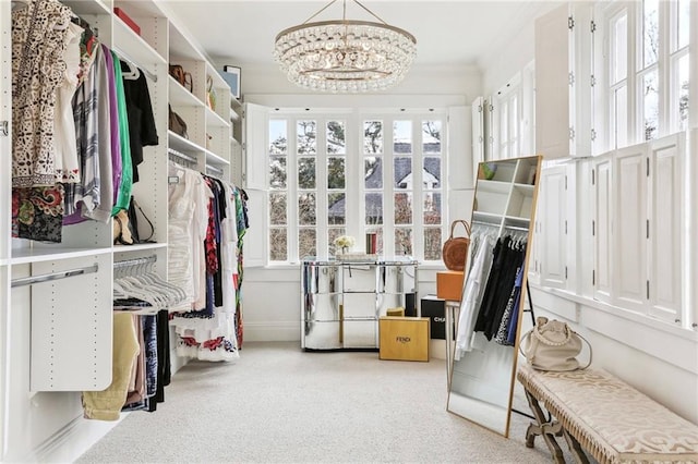 spacious closet with light colored carpet and a chandelier