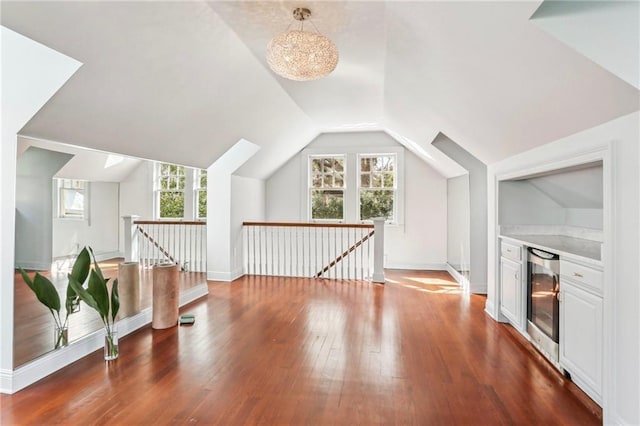 additional living space featuring dark hardwood / wood-style flooring, lofted ceiling, and beverage cooler