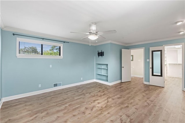 empty room featuring light wood-style flooring, visible vents, and ornamental molding