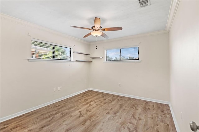 spare room featuring wood finished floors, a ceiling fan, baseboards, visible vents, and crown molding