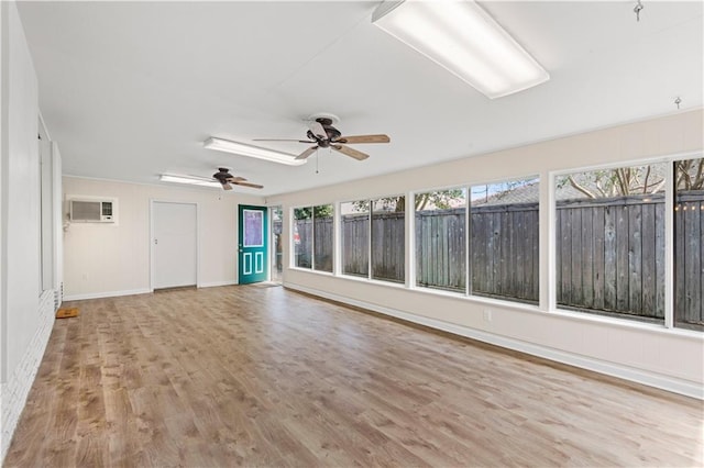 unfurnished sunroom featuring a ceiling fan and a wall mounted AC